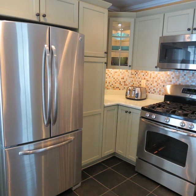 kitchen featuring stainless steel appliances, dark tile patterned flooring, light countertops, tasteful backsplash, and glass insert cabinets