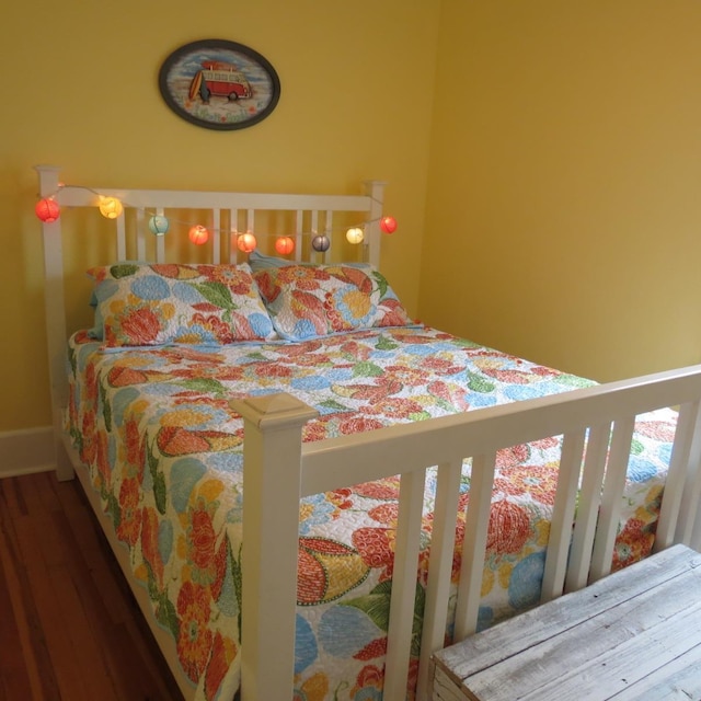 bedroom with wood finished floors and baseboards