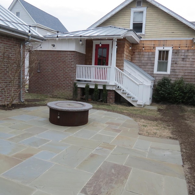 exterior space featuring metal roof, an outdoor fire pit, a standing seam roof, and a patio area