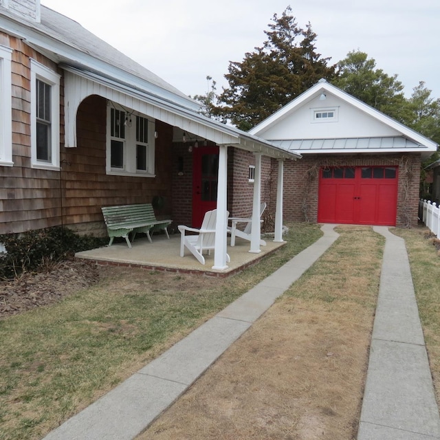 view of front of property featuring a garage, a patio, an outdoor structure, a front lawn, and brick siding