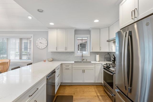 108 27th St, Avalon, NJ 08202 - kitchen featuring appliances with stainless steel finishes, a sink, under cabinet range hood, tasteful backsplash, and white cabinets