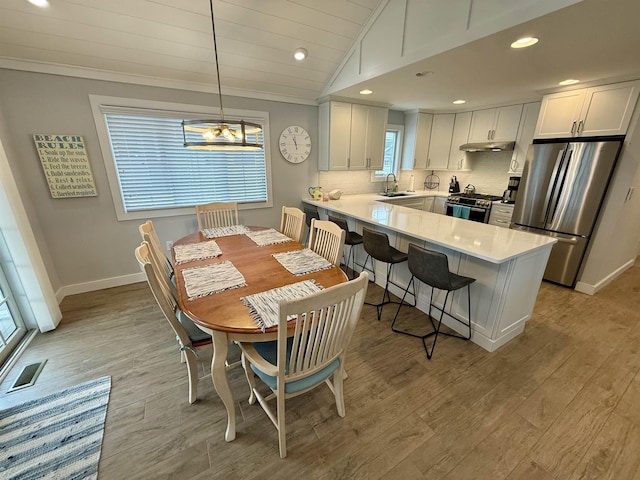 dining room with light wood finished floors, recessed lighting, baseboards, lofted ceiling, and ornamental molding