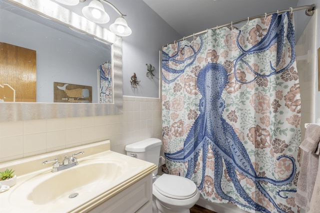 bathroom with vanity, toilet, and tile walls