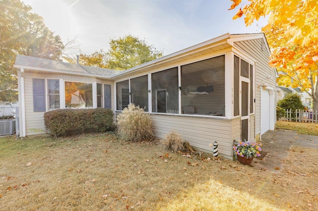 back of property featuring a sunroom, cooling unit, and a garage