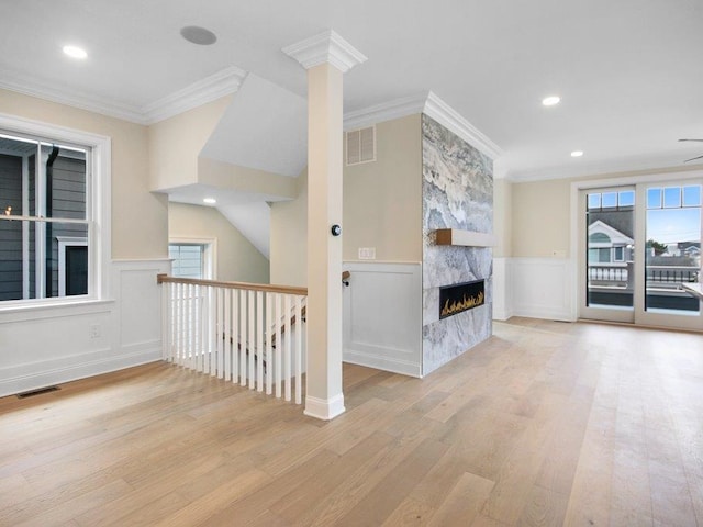 unfurnished living room featuring ornamental molding, a healthy amount of sunlight, and light hardwood / wood-style flooring