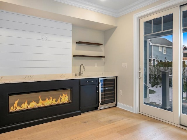 bar featuring crown molding, sink, wine cooler, and light hardwood / wood-style flooring