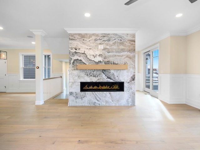 living room with crown molding, ceiling fan, a tiled fireplace, and light wood-type flooring