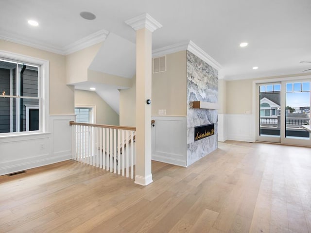 unfurnished living room with ornamental molding, a fireplace, and light wood-type flooring