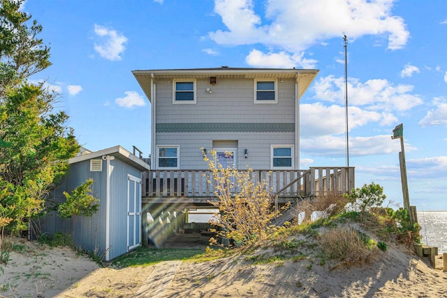 rear view of house with a storage unit and a deck