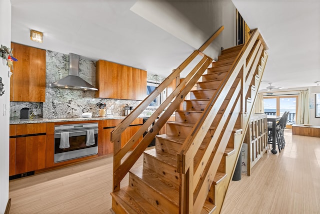 stairway featuring ceiling fan and wood-type flooring