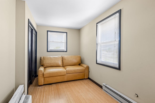 living room featuring plenty of natural light, a baseboard radiator, and light wood-type flooring