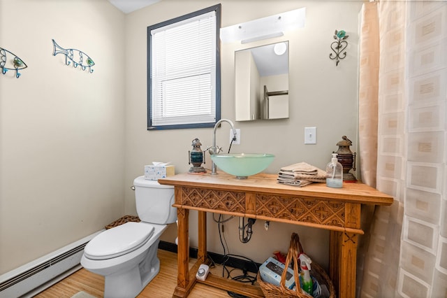 bathroom featuring hardwood / wood-style flooring, toilet, sink, and a baseboard heating unit