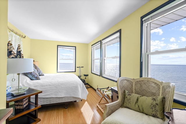 bedroom featuring wood-type flooring and a water view