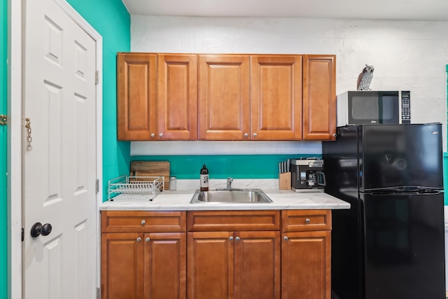 kitchen featuring black refrigerator and sink