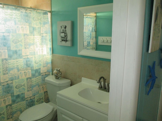 bathroom featuring vanity, tile walls, and toilet