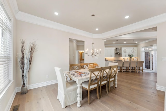 dining room with light wood finished floors, visible vents, baseboards, and ornamental molding