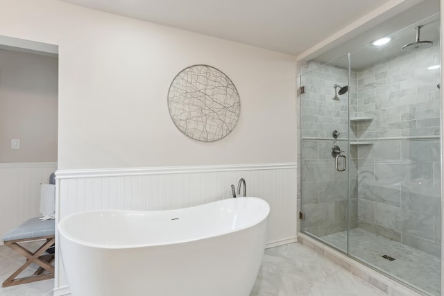 full bathroom featuring a shower stall, a freestanding tub, a wainscoted wall, and marble finish floor