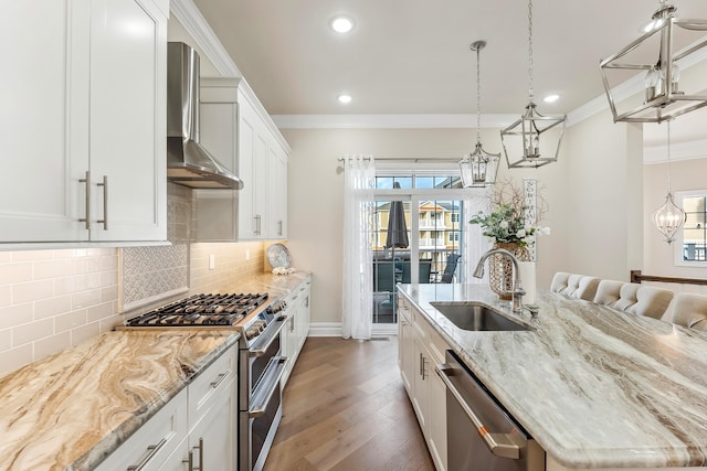 kitchen featuring ornamental molding, stainless steel appliances, wall chimney exhaust hood, and a sink