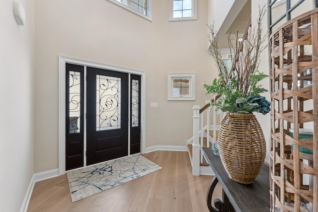 entryway with stairway, baseboards, and light wood-type flooring