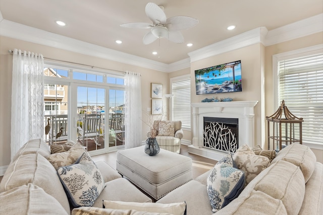 living room featuring plenty of natural light, a fireplace with raised hearth, wood finished floors, and crown molding