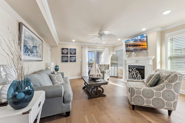 living area featuring ornamental molding, recessed lighting, a fireplace, wood finished floors, and a ceiling fan