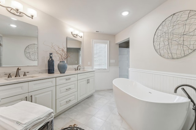 full bath featuring double vanity, a wainscoted wall, visible vents, and a sink