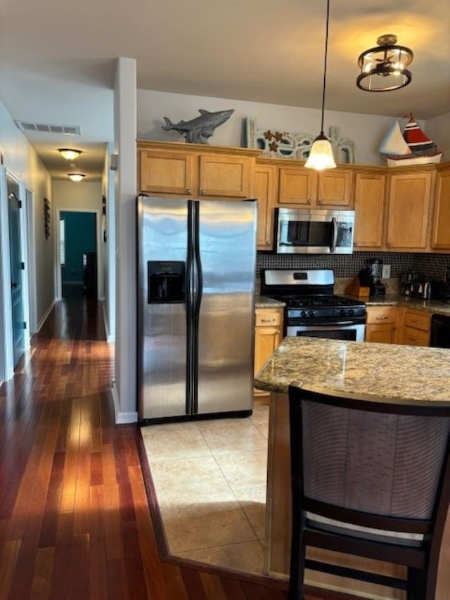 145 W Andrews Ave Unit 100, Wildwood, NJ 08260 - kitchen with appliances with stainless steel finishes, light stone counters, backsplash, light wood finished floors, and hanging light fixtures