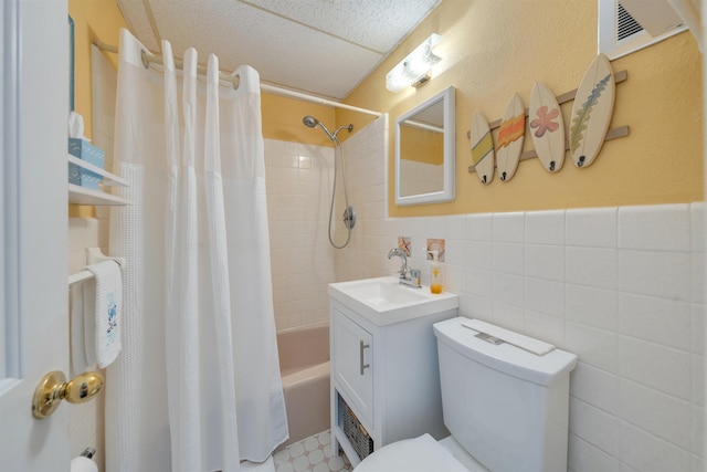 full bathroom with vanity, shower / bath combo, tile walls, and toilet