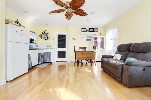 living room featuring wood-type flooring, ornamental molding, and ceiling fan