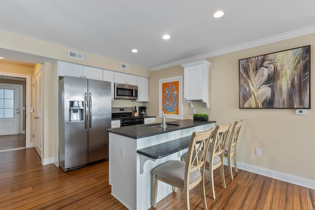 kitchen featuring appliances with stainless steel finishes, dark hardwood / wood-style floors, white cabinetry, sink, and kitchen peninsula