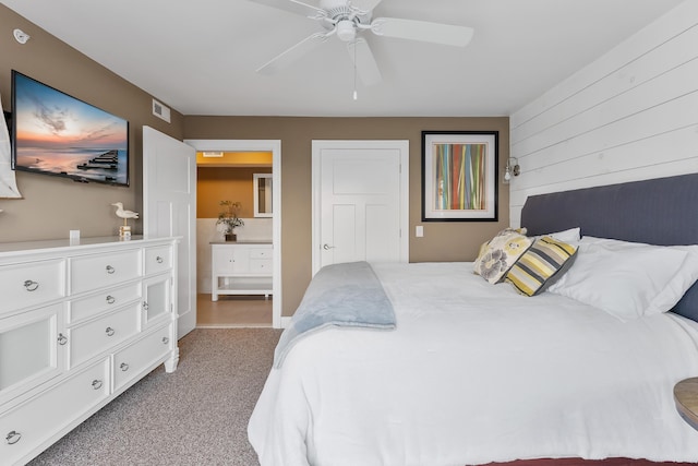 carpeted bedroom with ensuite bathroom and ceiling fan