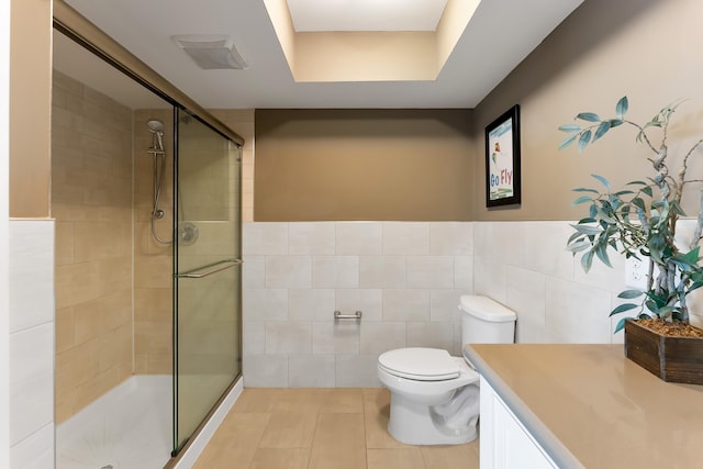 bathroom featuring tile walls, vanity, toilet, and walk in shower