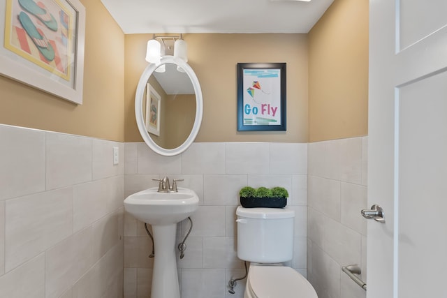 bathroom featuring tile walls and toilet