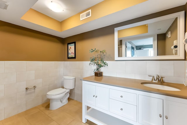 bathroom featuring vanity, toilet, tile patterned flooring, and tile walls