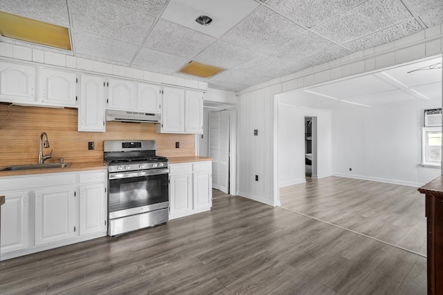 kitchen featuring exhaust hood, sink, white cabinetry, and stainless steel range with gas stovetop