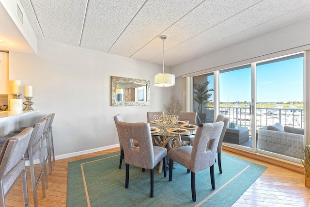 dining space featuring wood-type flooring, visible vents, and baseboards