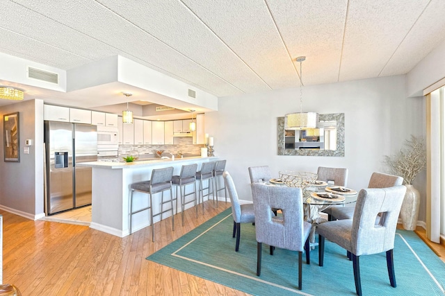 dining space featuring baseboards, visible vents, and light wood finished floors