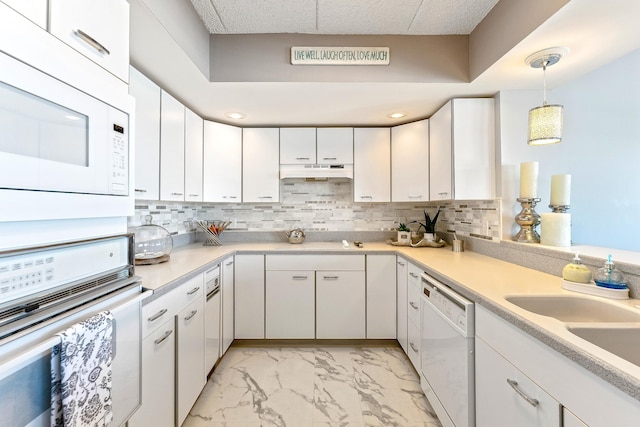 kitchen featuring marble finish floor, white appliances, backsplash, and under cabinet range hood