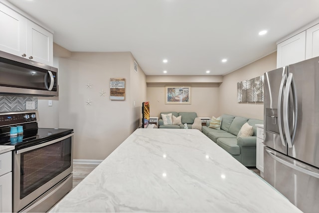 kitchen with white cabinets, dark wood-type flooring, light stone countertops, and appliances with stainless steel finishes