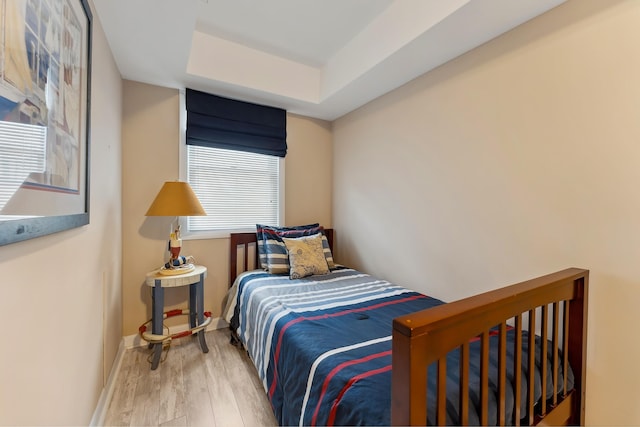 bedroom with wood-type flooring and a tray ceiling