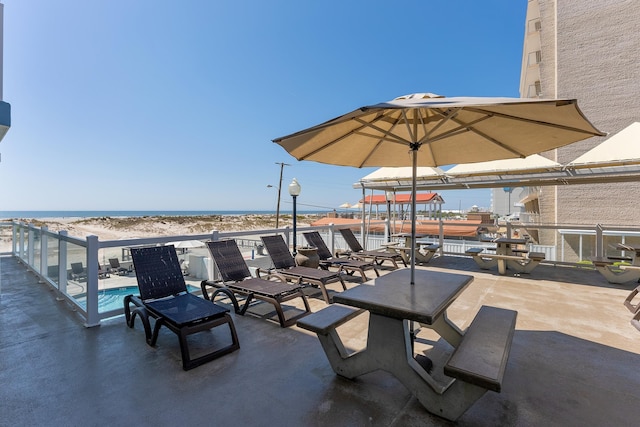 view of patio / terrace featuring a water view and a beach view