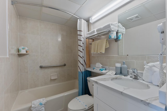 full bathroom with shower / tub combo with curtain, tile walls, vanity, decorative backsplash, and a drop ceiling