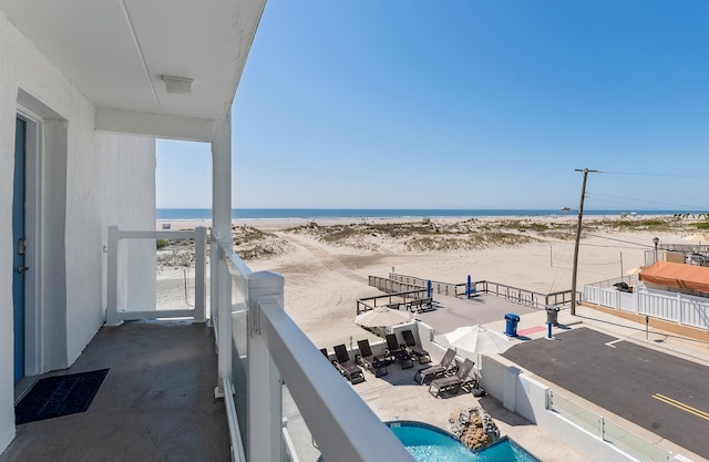 balcony with a water view and a view of the beach