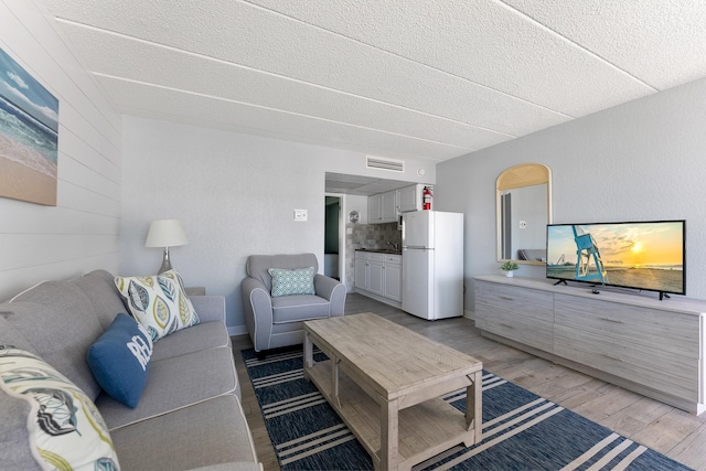 living room with light hardwood / wood-style flooring and a textured ceiling