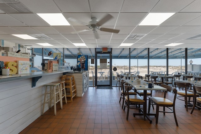 dining space with a water view, a paneled ceiling, and ceiling fan