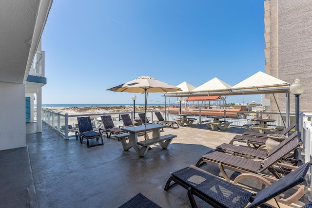 view of patio / terrace featuring a water view, a balcony, and a beach view