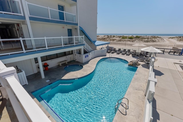 view of swimming pool featuring a water view and a patio