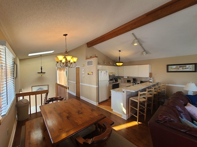 dining room with sink, hardwood / wood-style flooring, a notable chandelier, lofted ceiling with beams, and a textured ceiling