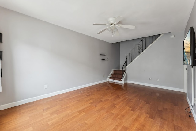 unfurnished living room with stairway, wood finished floors, baseboards, and ceiling fan