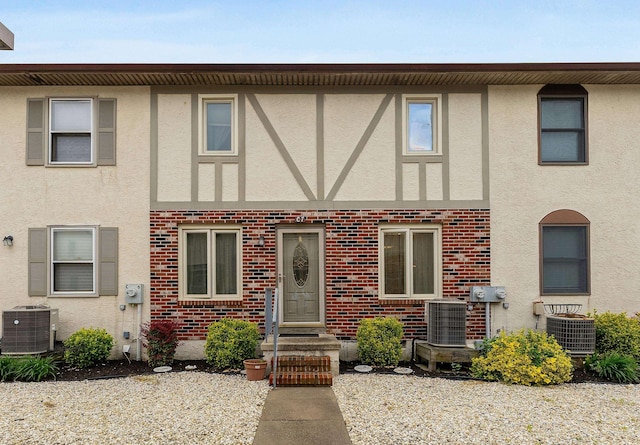 view of front of property with stucco siding, central air condition unit, and brick siding